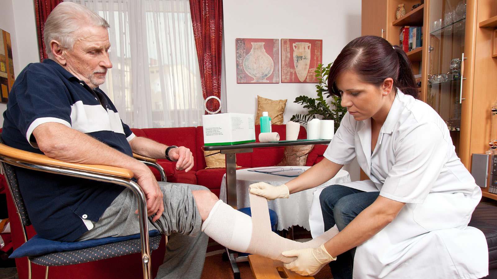 Krankenschwester versorgt ein Wunde am Bein des Kunden